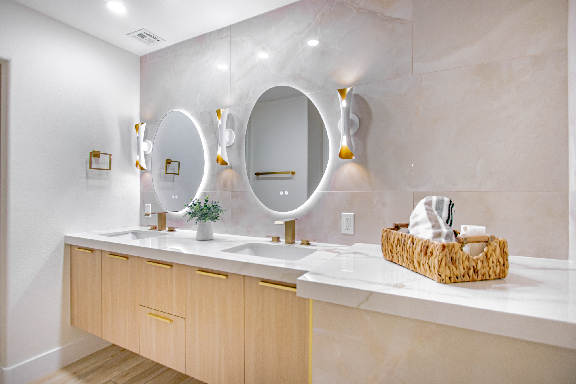 Bathroom remodel with dual backlit round mirrors and a floating double vanity by Nevada Pro Construction