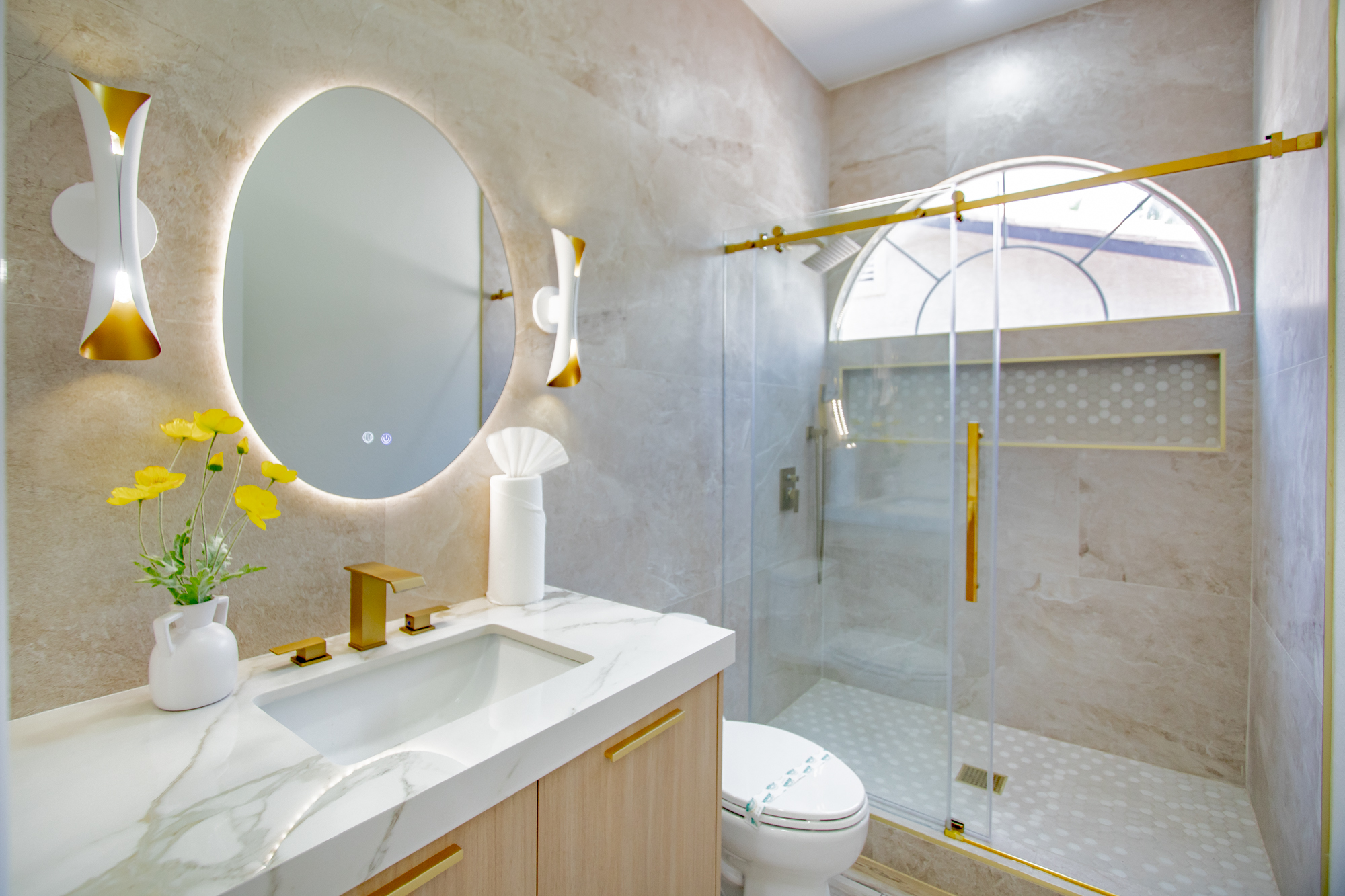 Bathroom remodel with a backlit oval mirror, marble-look walls, and a walk-in glass shower by Nevada Pro Construction