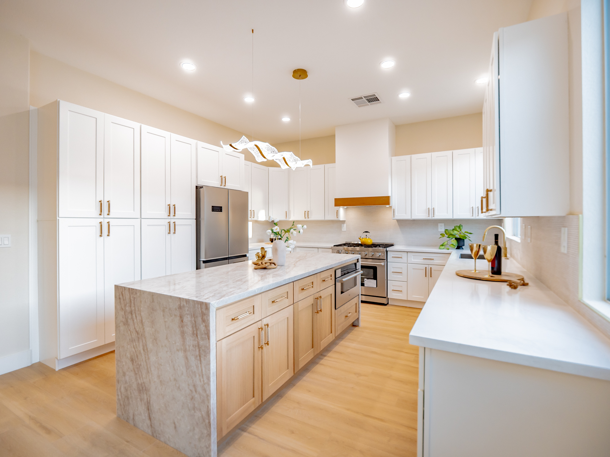 White shaker kitchen remodel with a waterfall marble island and gold hardware by Nevada Pro Construction